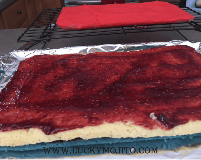 spreading raspberry jam on rainbow cookie